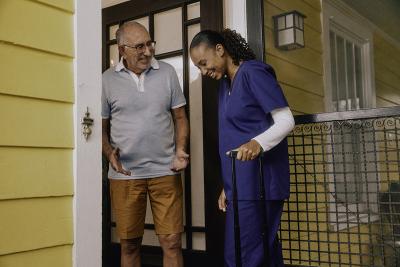 An older man welcoming a medical professional into his home