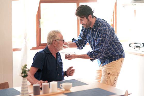 A man giving an older man medicine
