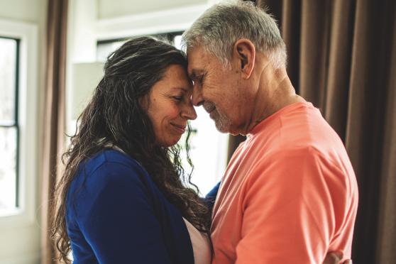 A man and woman standing with their foreheads touching.