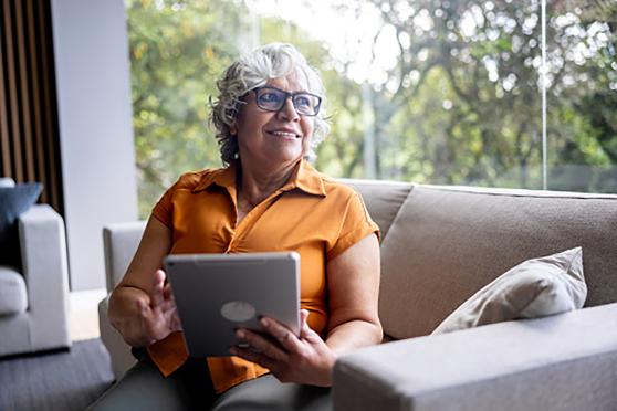 A woman sitting on a couch holding a tablet.